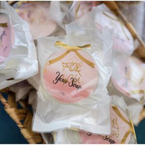 A basket of pink and white cookies with gold bow.