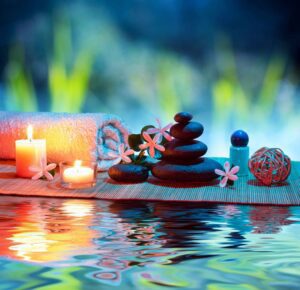 stacked stones, a rolled towel, two lit candles floating on water