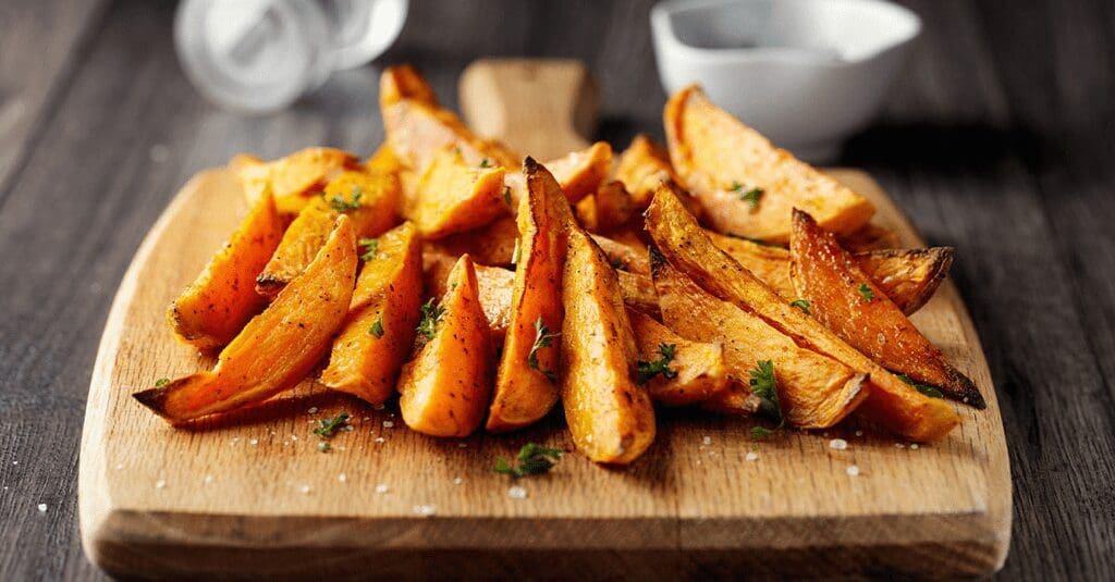 A wooden cutting board topped with cut up potatoes.