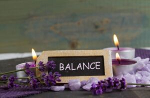 A sign that says balance with candles and lavender.
