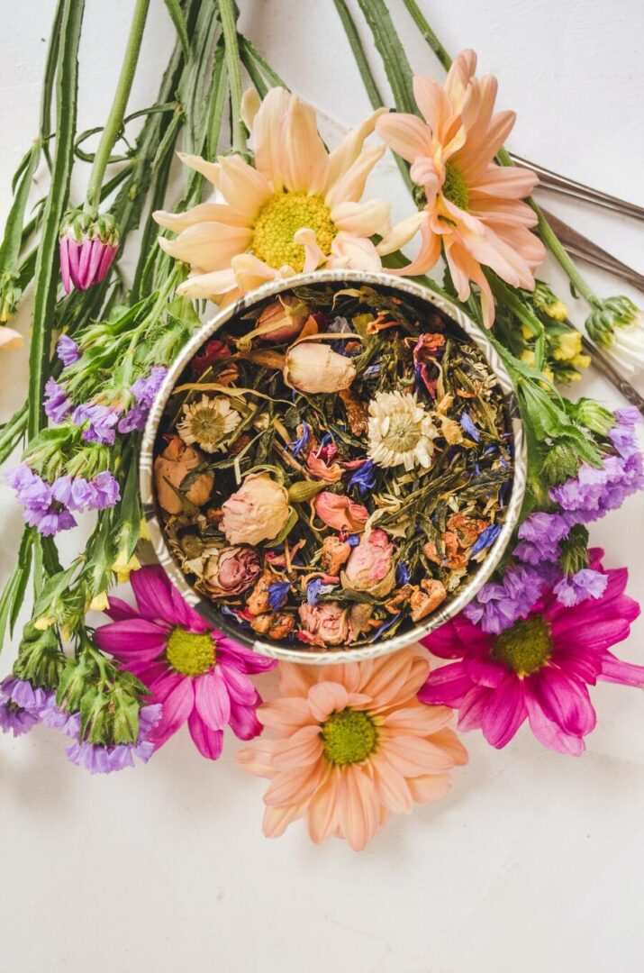 A bowl of tea surrounded by flowers on the table.