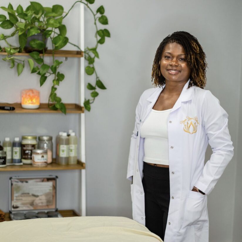 A woman in white lab coat standing next to table.